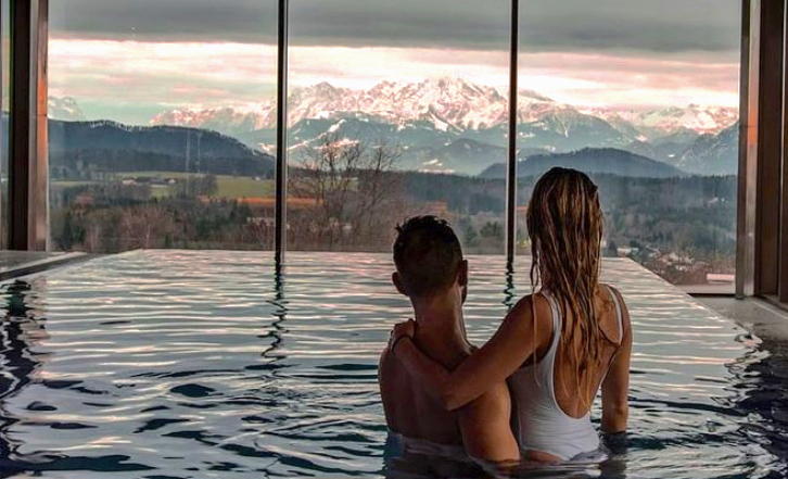 Zwei Personen schauen auf das Bergpanorama vom Pool aus