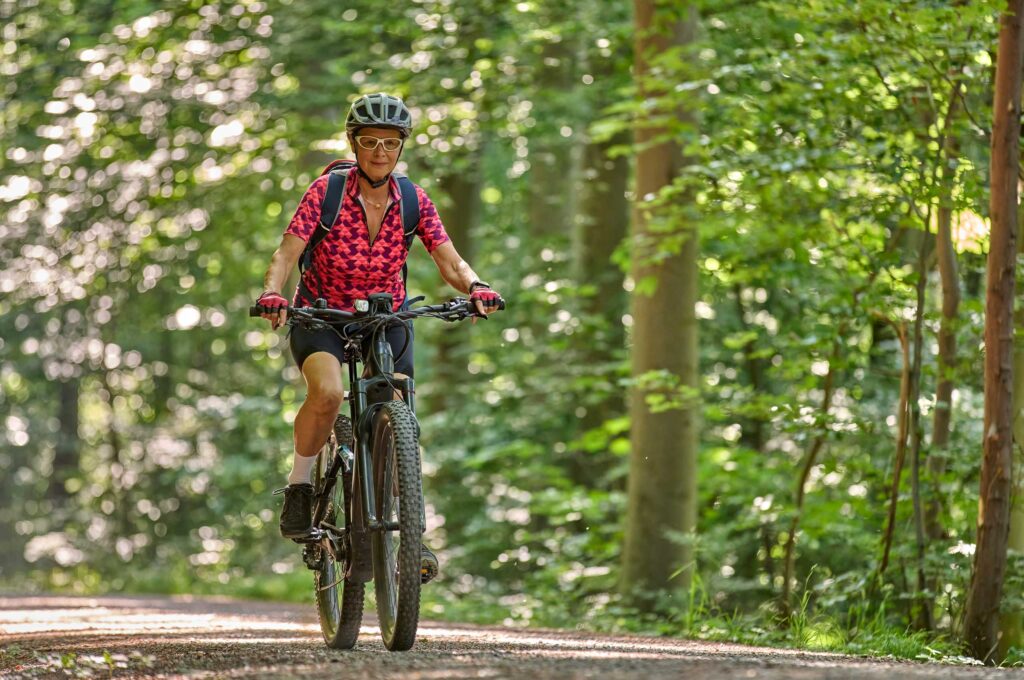 Frau fährt auf E-Bike im Wald