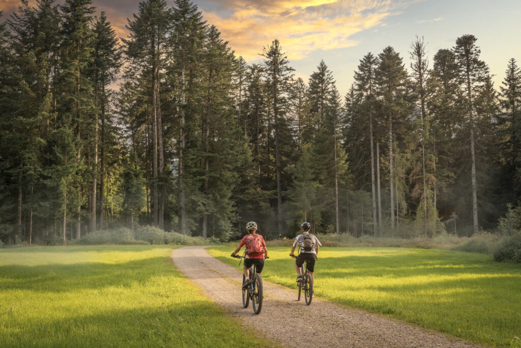 Paar bei E-Bike-Tour in Salzburg auf Wiese mit Wald